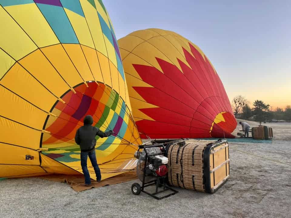 Preparing for a hot air balloon flight with colorful balloons inflating at dawn